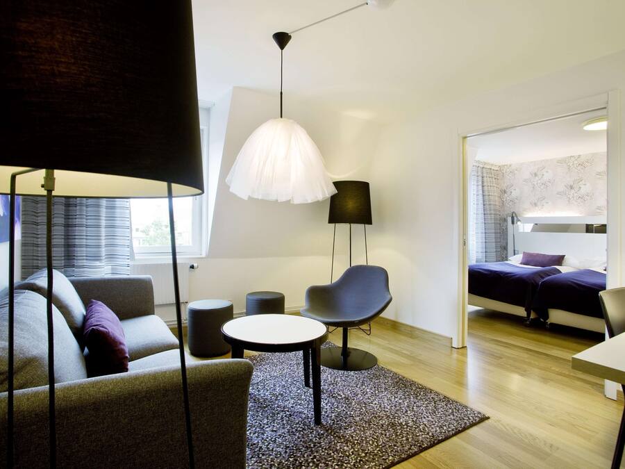 Quarto moderno com sofá, mesa redonda, cadeira, abajur e cama.