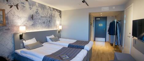 A hotel room with two beds, a large wall mural, a desk, and a chair.