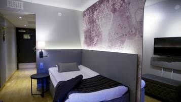 Habitación de hotel moderna con cama, una mesita, televisión y un gran cuadro abstracto en la pared.