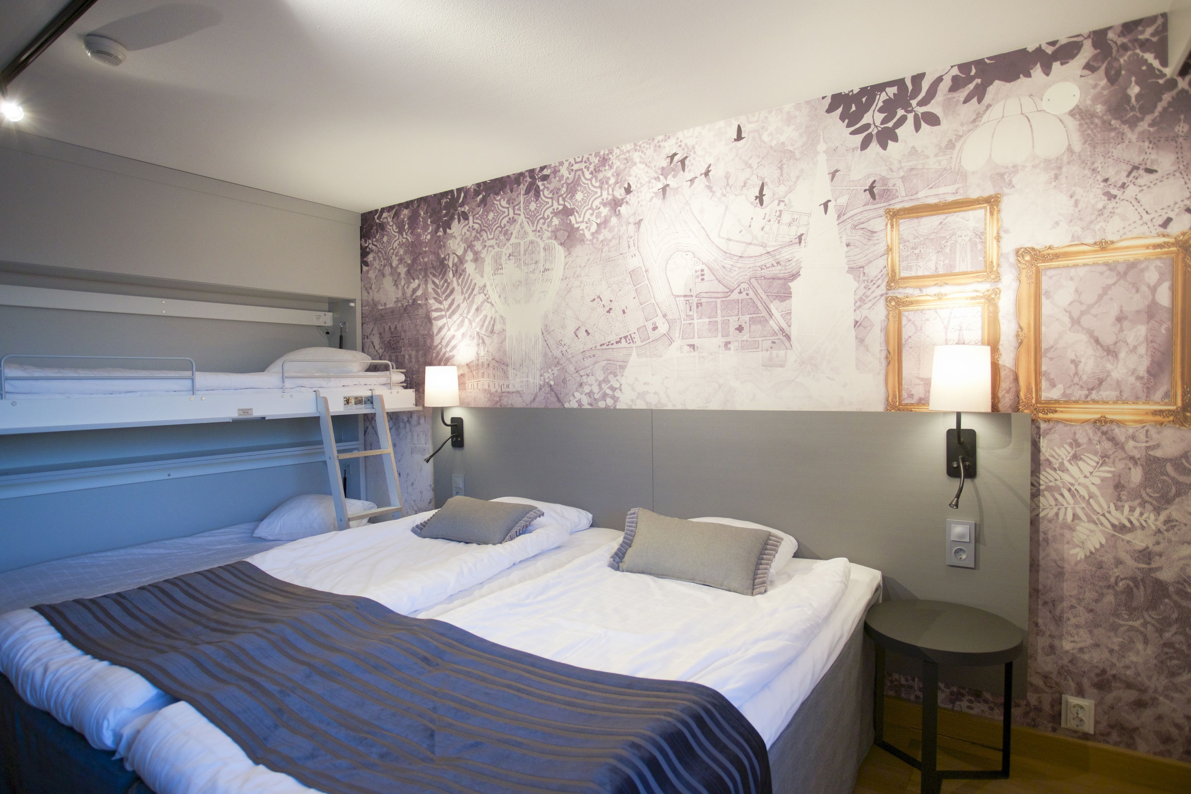 A hotel room with a bunk bed, a desk, and a small table.