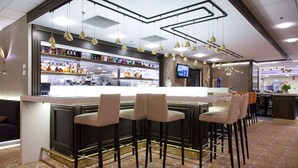 Eine Bar mit einer Theke, Barhocker und einem Fernsehbildschirm.