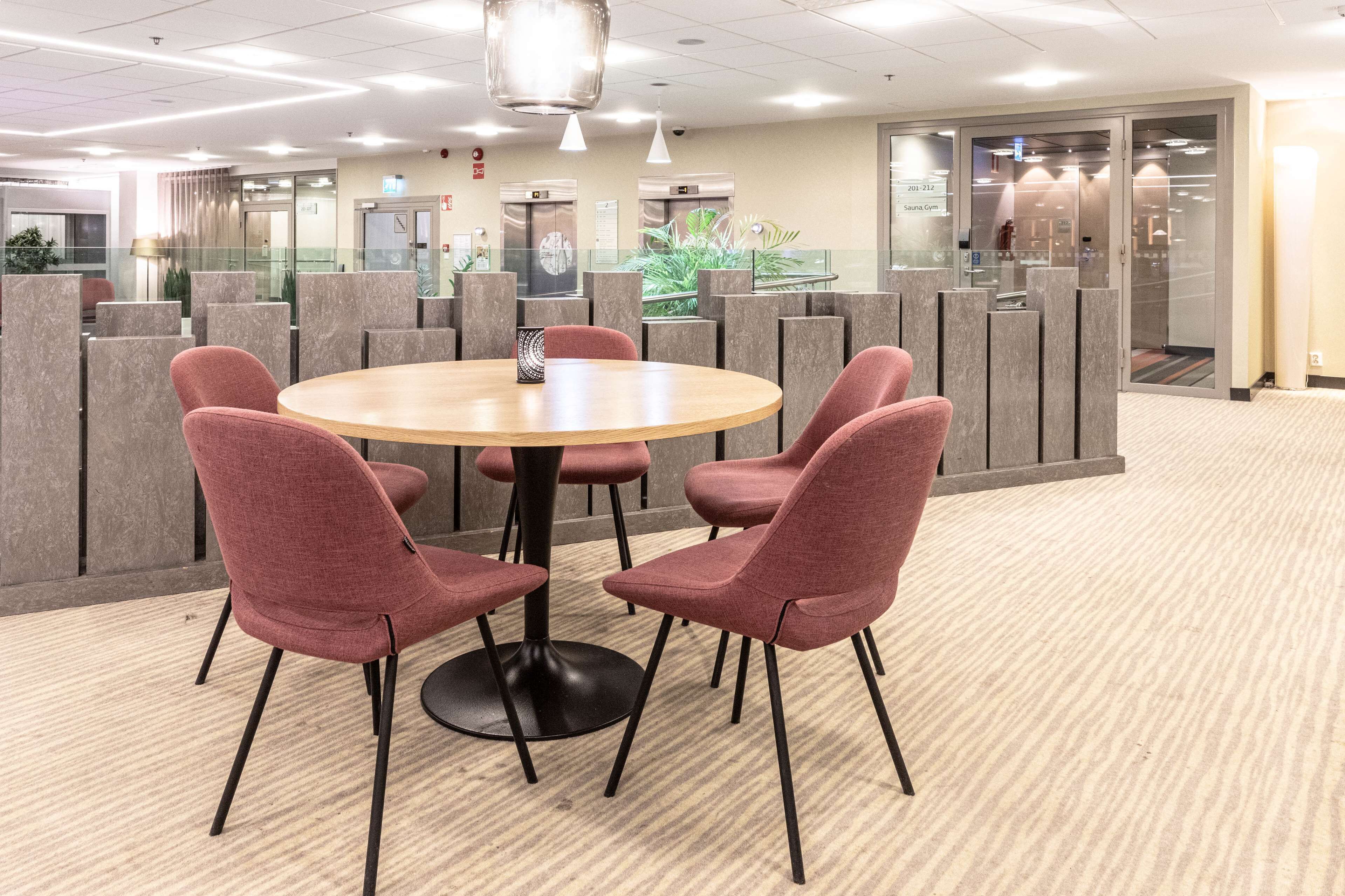 A conference room with a round table, four red chairs, and a modern ceiling design.