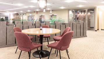 A conference room with a round table, four red chairs, and a modern ceiling design.
