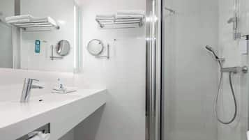 A modern bathroom with a white sink, mirror, and glass shower enclosure.