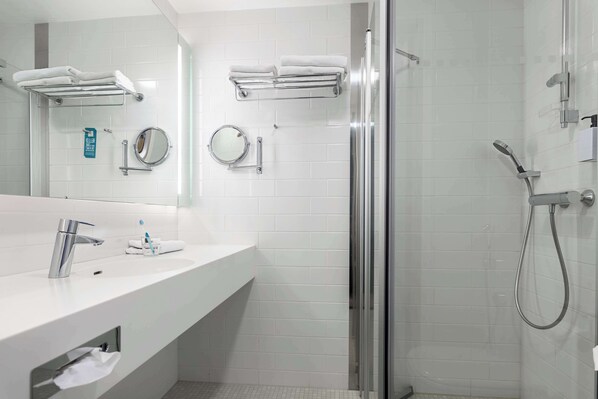 Ein modernes Badezimmer mit Waschbecken, Spiegel und Duschkabine aus Glas.