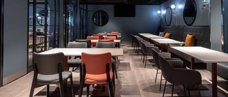 Un restaurant moderne avec un long comptoir, de nombreuses tables et des chaises.