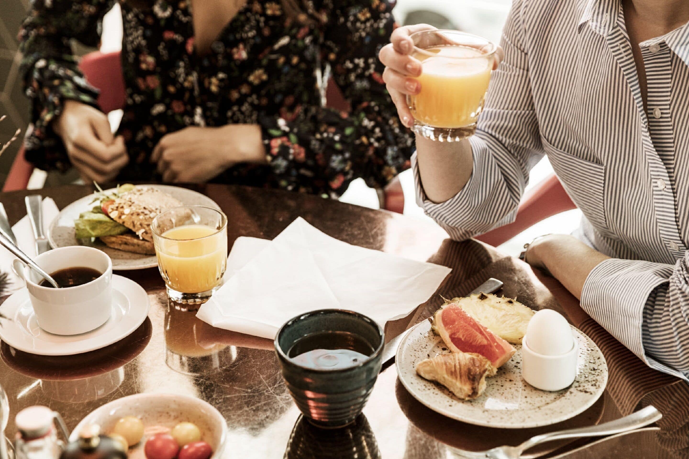 A breakfast setting with a table, plates, cups, and a coffee pot.