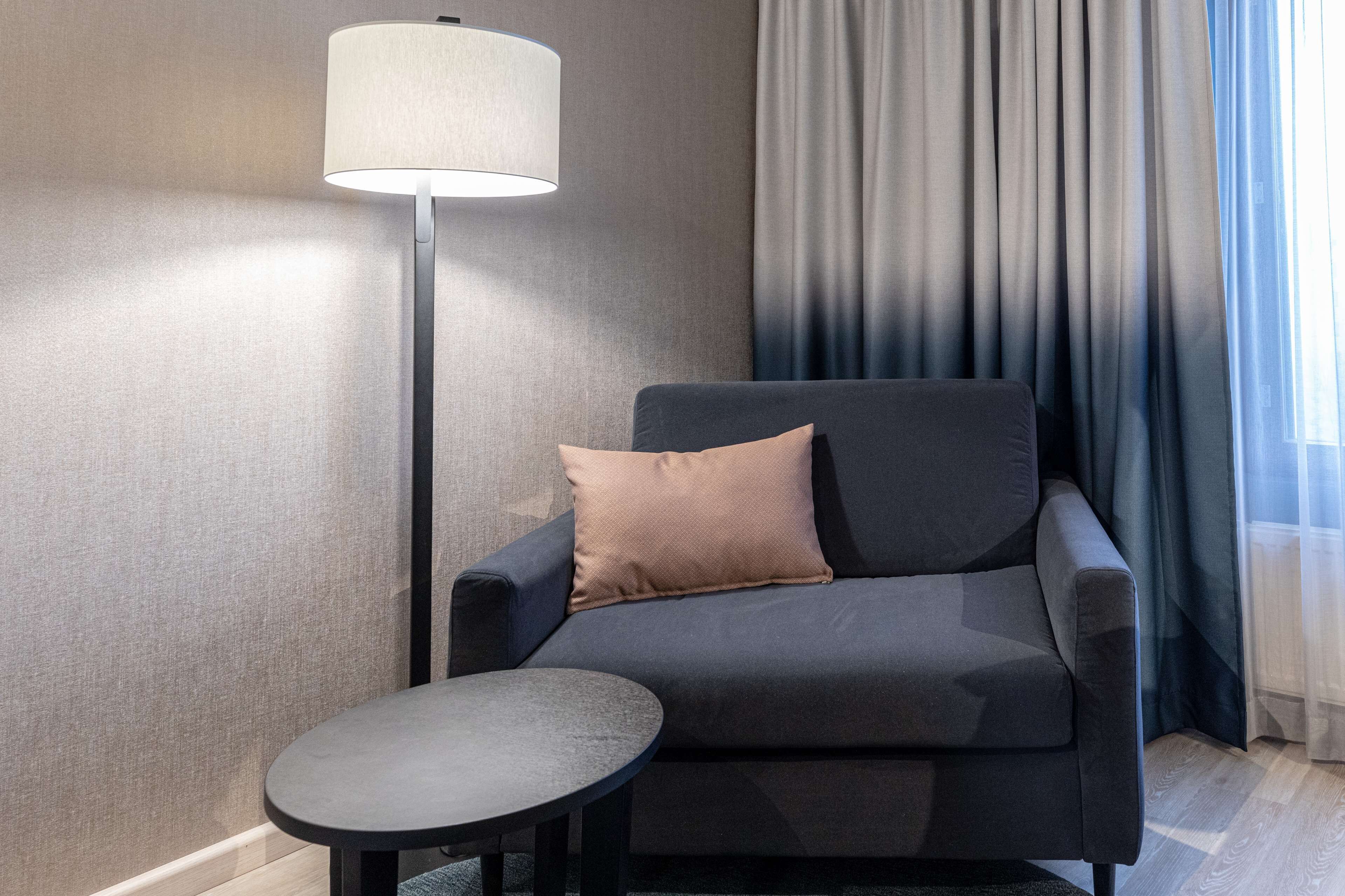 Une pièce moderne avec un canapé gris, une petite table ronde et un lampadaire.