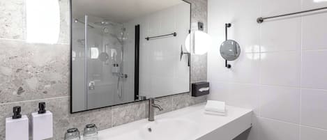 A modern bathroom with a large mirror, a sink, and a glass shower enclosure.
