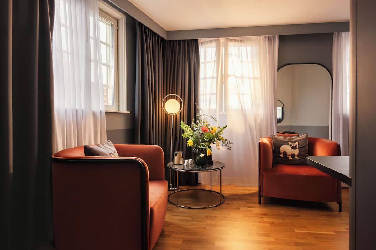 A modern living room with two red sofas, a round coffee table, and a floor lamp.