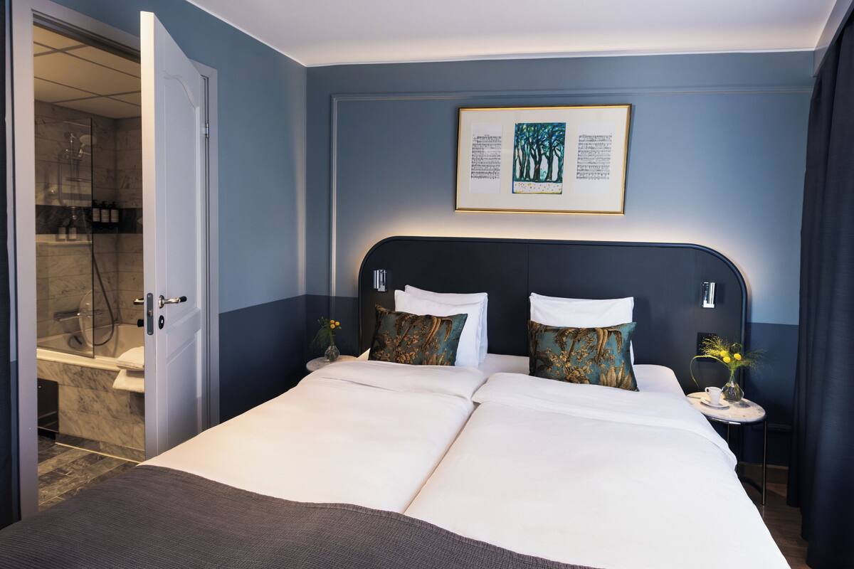 A hotel room with a large bed, a shower, and a framed picture on the wall.
