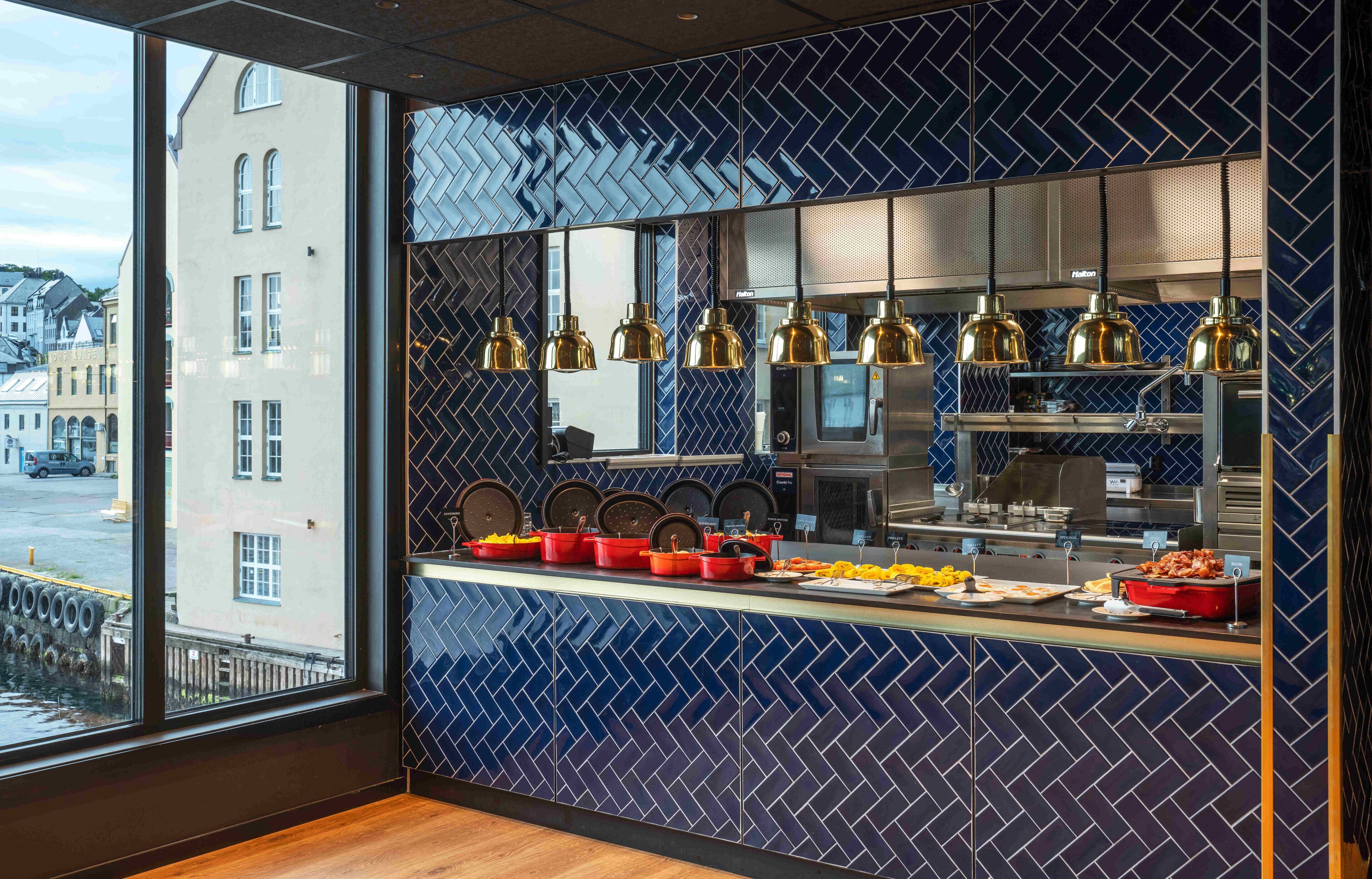 A modern kitchen with a blue patterned backsplash, stainless steel appliances, and a buffet counter with various dishes.