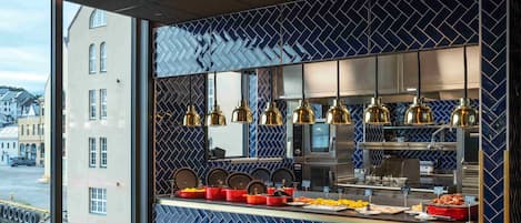 A modern kitchen with a blue patterned backsplash, stainless steel appliances, and a buffet counter with various dishes.