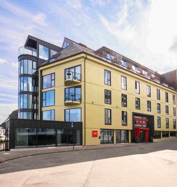 A modern hotel with multiple floors, large windows, and a prominent red sign.