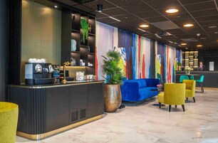 Un área de recepción moderna con mostrador, asientos y un mural colorido.