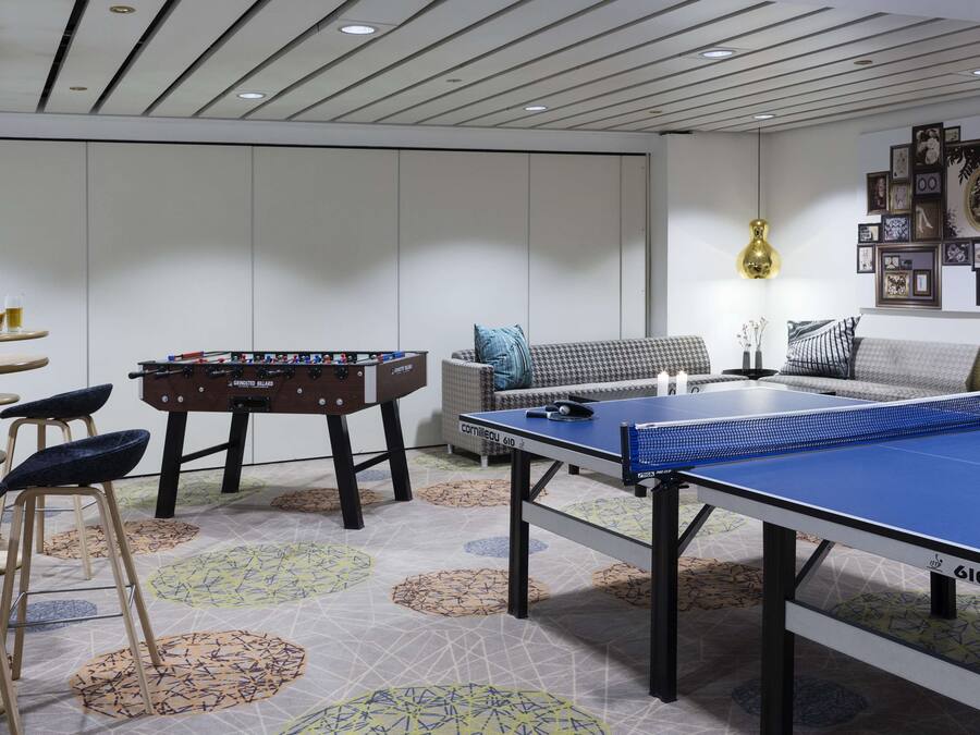 Une pièce équipée d’un baby-foot, d’une table de ping-pong et de tabourets de bar.