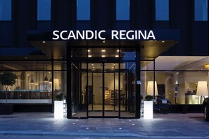 La façade extérieure de l’hôtel Scandic Regina, avec son entrée en verre, un vélo garé devant et une enseigne au-dessus de l’entrée.