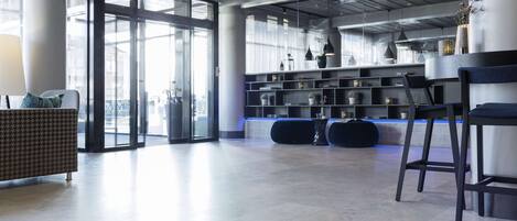 A modern lobby with a seating area, a reception desk, and a large glass door leading outside.