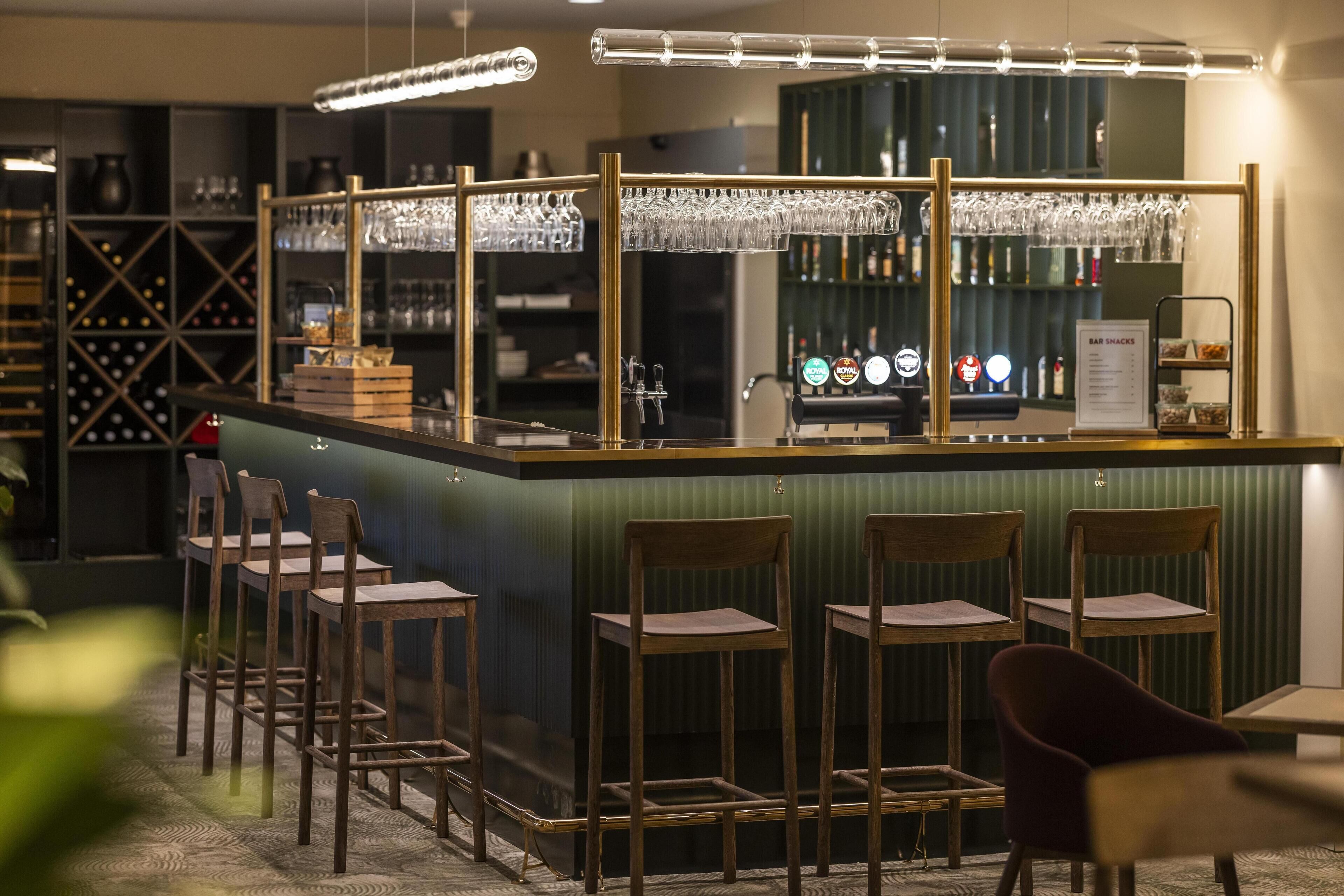 A bar area with stools, a bar counter, and a wine rack in the background.