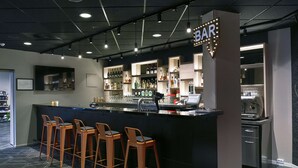 A bar area with a counter, stools, and a variety of bottles and glasses. - Scandic Aarhus Vest (Aarhus)