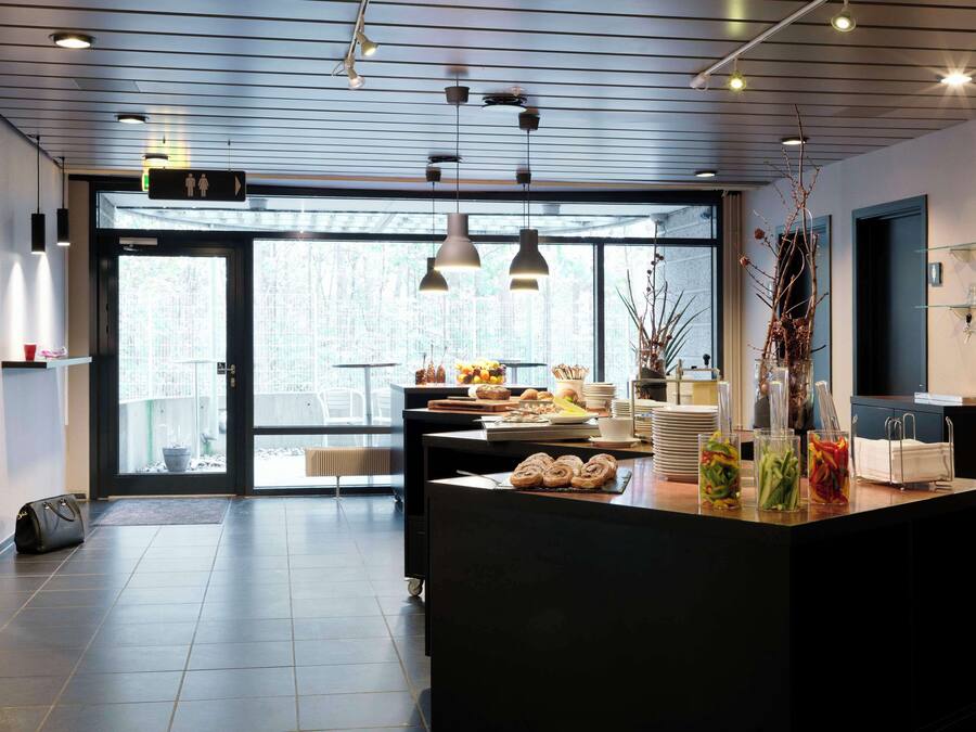 Eine moderne Hotelhalle mit einer Rezeption, einem großen Fenster und Blick ins Freie.