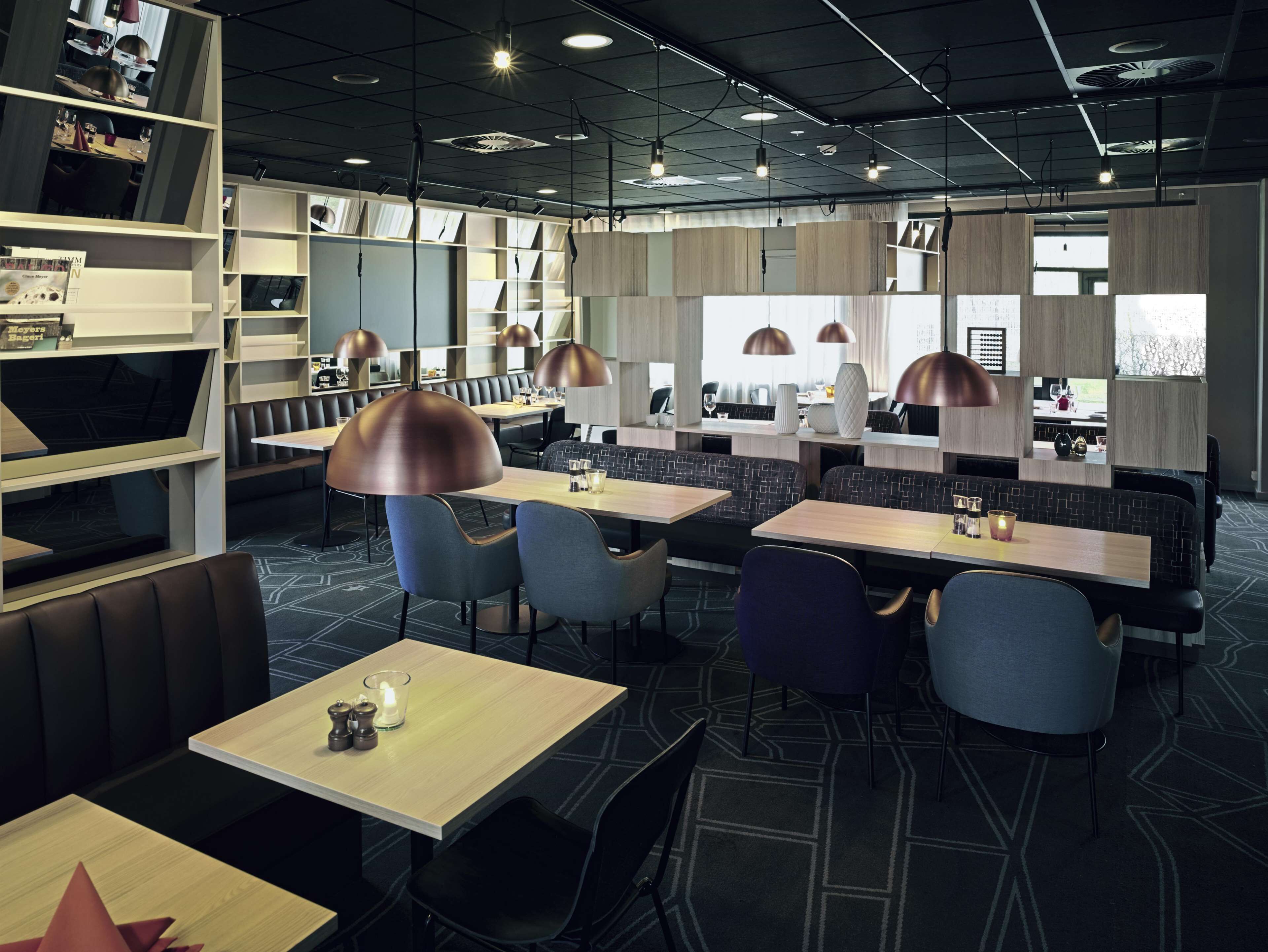 A modern restaurant with booths and tables, pendant lighting, and a patterned floor.