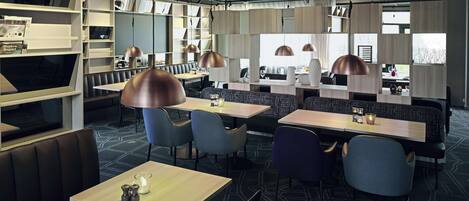 A modern restaurant with booths and tables, pendant lighting, and a patterned floor.