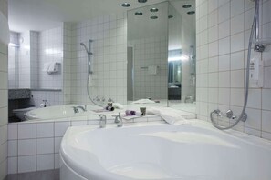 A modern bathroom with a large bathtub, a double sink, and a walk-in shower. - Scandic Aarhus Vest (Aarhus)
