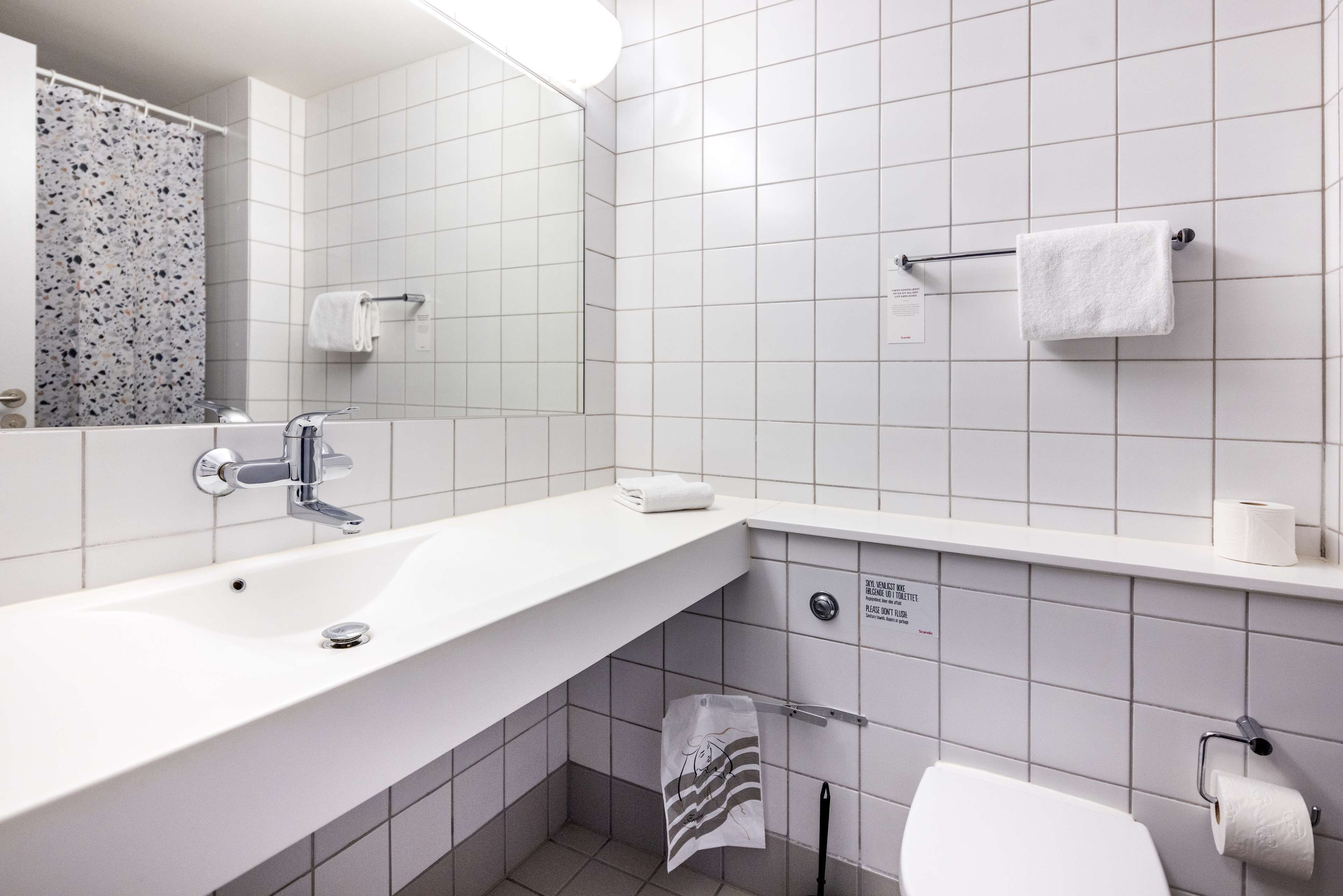 A modern bathroom with a white sink, mirror, and towel rack.