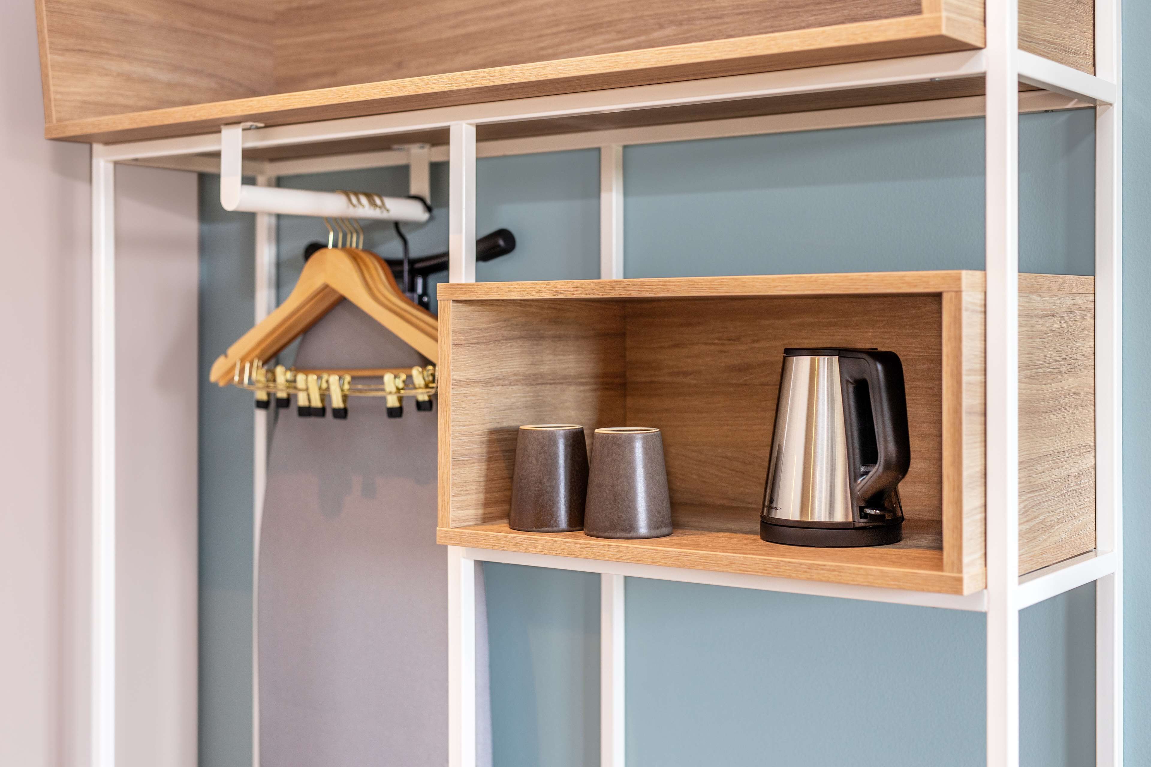 A wooden shelf with a kettle and two mugs.
