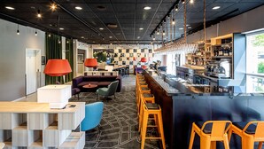 A modern bar area with a bar counter, stools, and seating. - Scandic Roskilde Park (Roskilde)