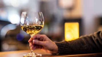 Una mano sosteniendo una copa de vino sobre una superficie de madera.