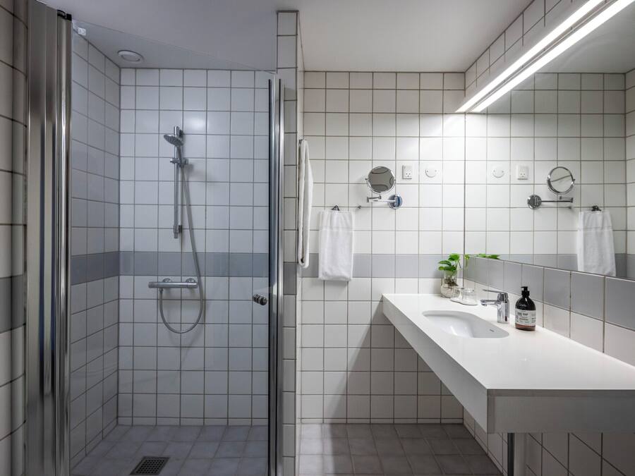 A modern bathroom with a glass-enclosed shower, a white sink, and a mirror above the sink.