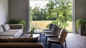 A modern living room with a large window, a sofa, a coffee table, and two chairs. - Comwell Bygholm Park (Horsens)