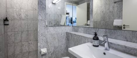 Un baño moderno con lavamanos, espejo y váter blancos.