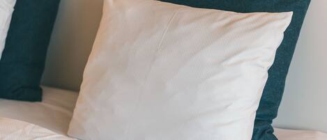 Una cama con almohadas blancas y verde oscuro.