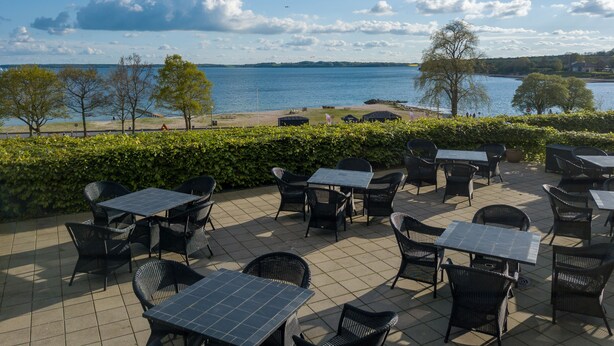 An outdoor patio with tables and chairs overlooking a lake.