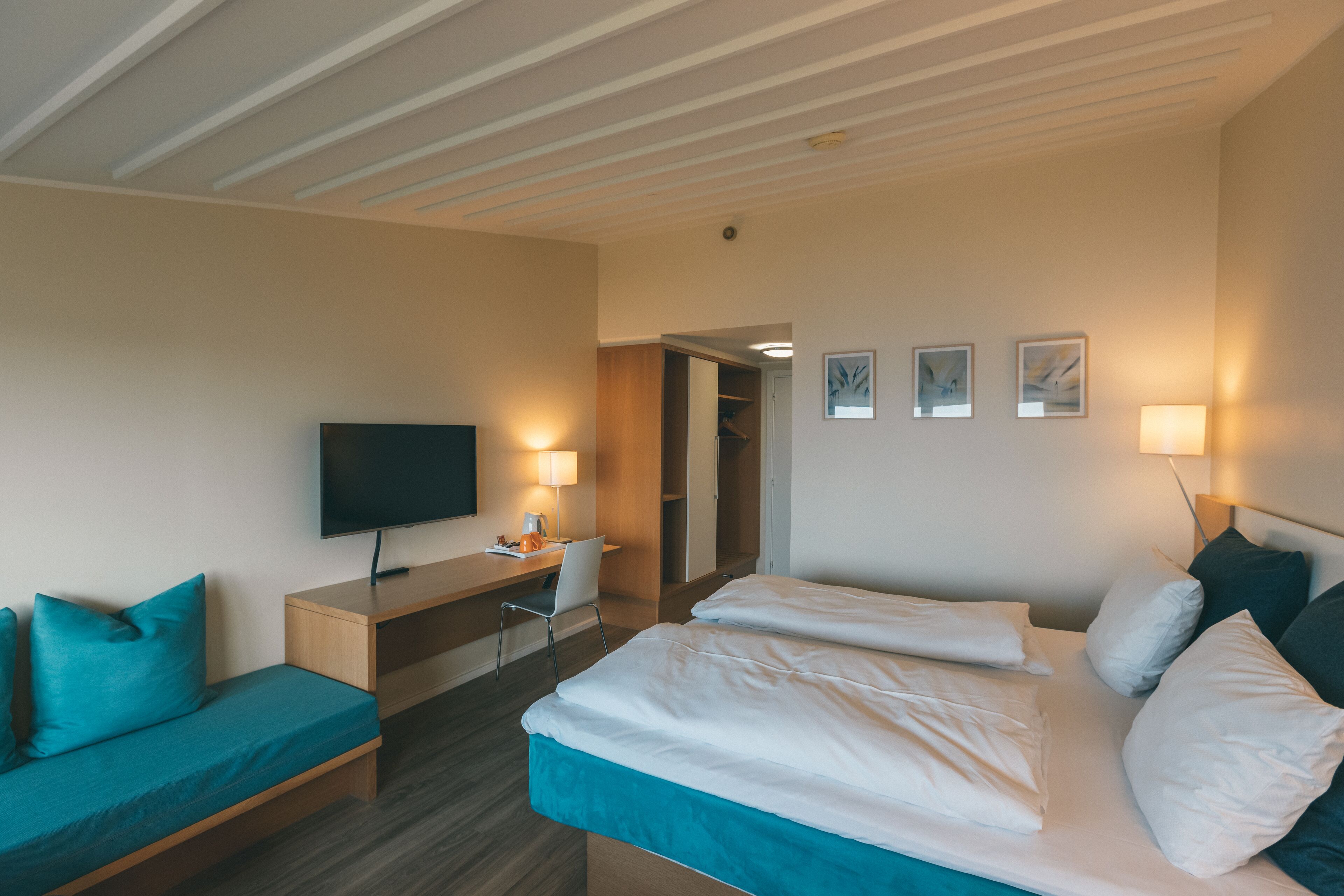 Une chambre d’hôtel avec un lit, un bureau avec une télévision, une chaise et un canapé.