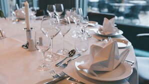 A table set for a formal dinner with wine glasses, cutlery, and a candle.