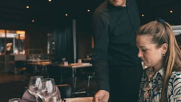 A restaurant setting with a table set for two, including wine glasses, plates, and cutlery.