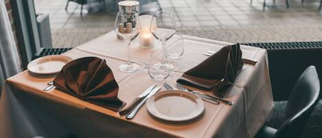 A table set for two with a candle, wine glasses, and cutlery.