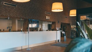 A reception area with a brick wall, a white reception desk, and a large clock.