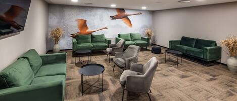 A waiting area with green sofas, armchairs, and a carpeted floor.