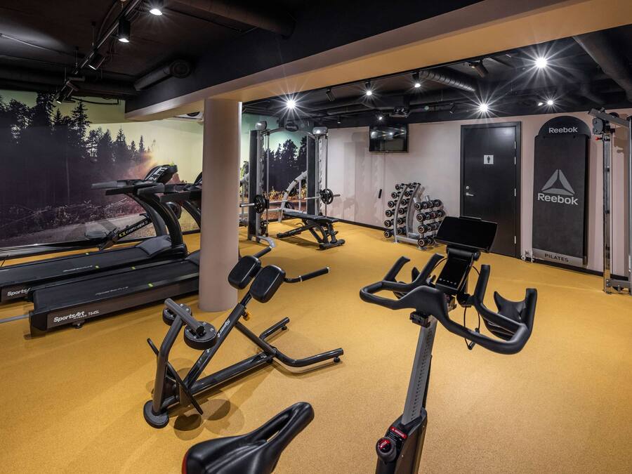Un gimnasio con cintas de correr, elípticas y equipo de levantamiento de pesas.