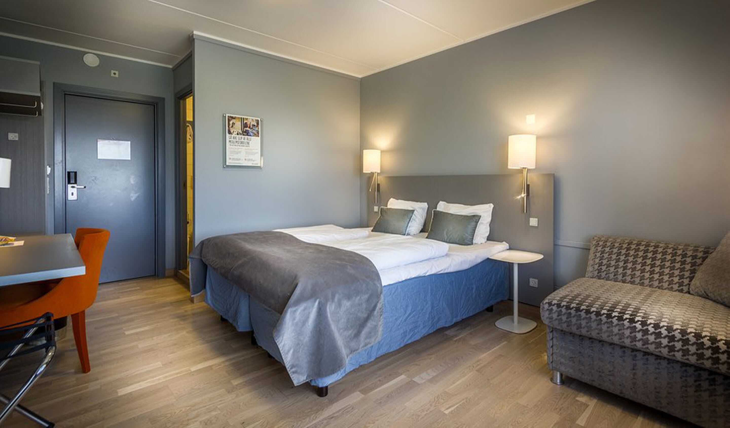 Una habitación de hotel con cama, escritorio y sofá.