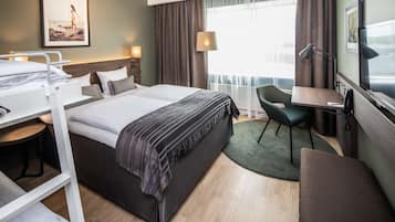 Habitación de hotel con cama, escritorio, silla y vistas al exterior.