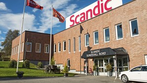 Un bâtiment en briques sur lequel on peut voir une grande enseigne « Scandic », un drapeau et un vélo.