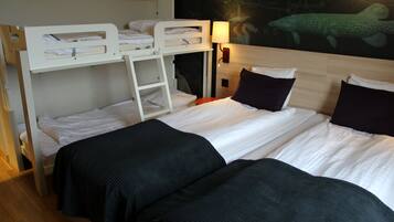 A hotel room with a bunk bed, a single bed, a nightstand with a lamp, and a wall mural.