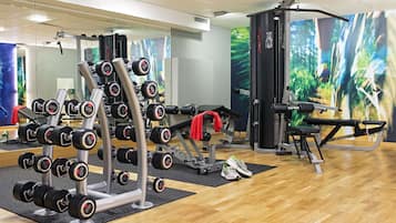 A gym with various exercise equipment, including dumbbells, a bench press, and a cable machine.