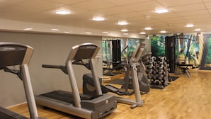 Une salle de sport équipée de tapis de course, de vélos elliptiques et de matériel de musculation.